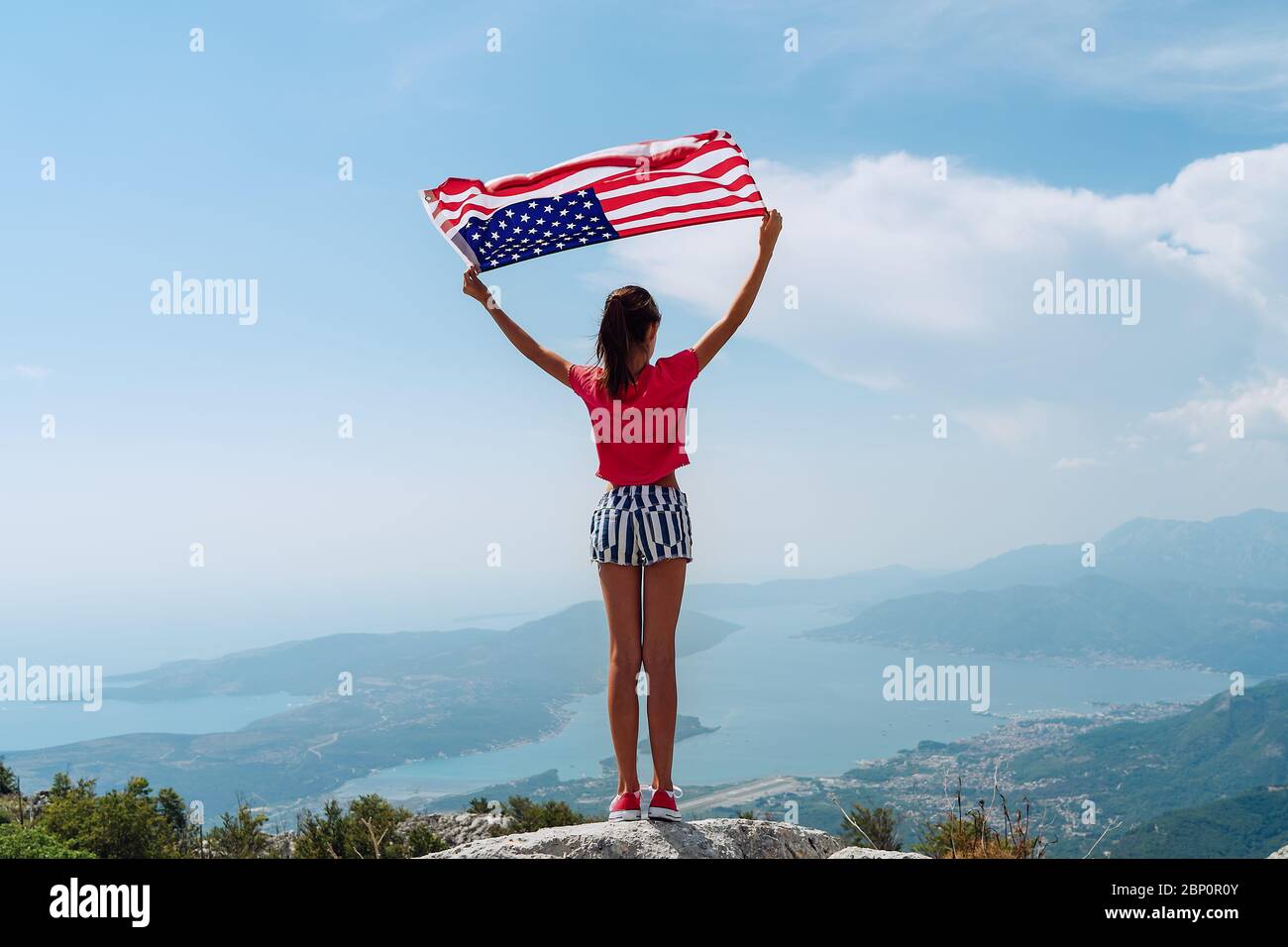 Kind Mädchen winkt amerikanische Flagge auf dem Gipfel des Berges am Himmel Hintergrund Stockfoto