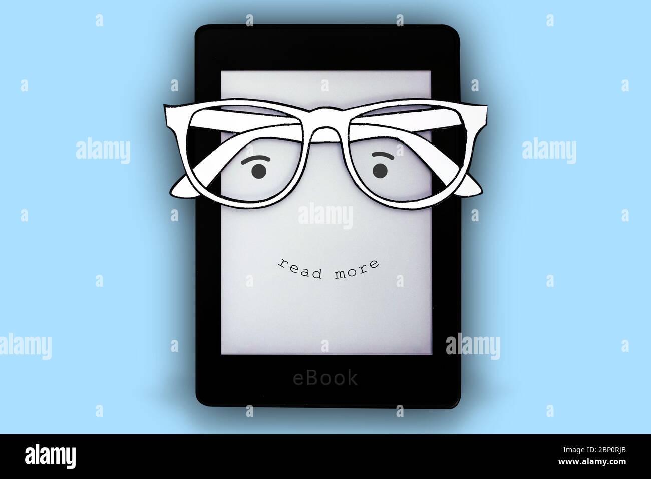 Ein schwarzes E-Book mit Papiergläsern und einem glücklichen Gesicht, wo es auf blauem Hintergrund 'mehr lesen' steht Stockfoto