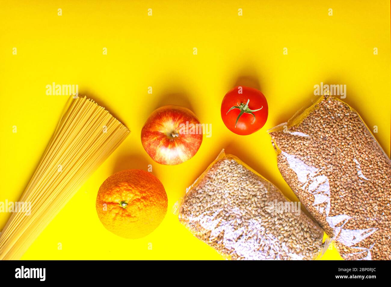 Lebensmittel für Quarantäne auf gelbem Hintergrund. Pasta, Gemüse, Obst, Getreide. Stockfoto