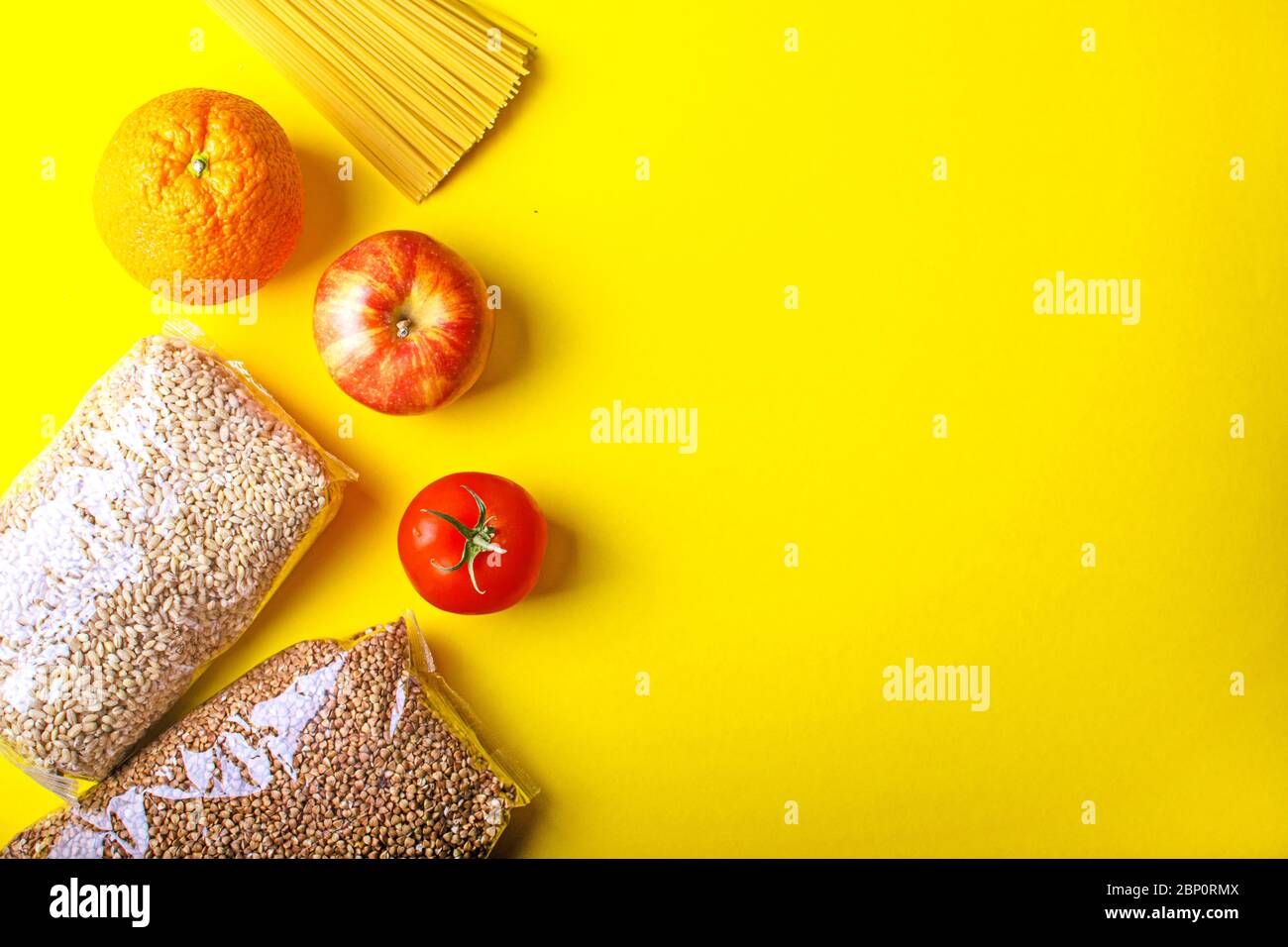 Lebensmittel für Quarantäne auf gelbem Hintergrund. Pasta, Gemüse, Obst, Getreide. Stockfoto