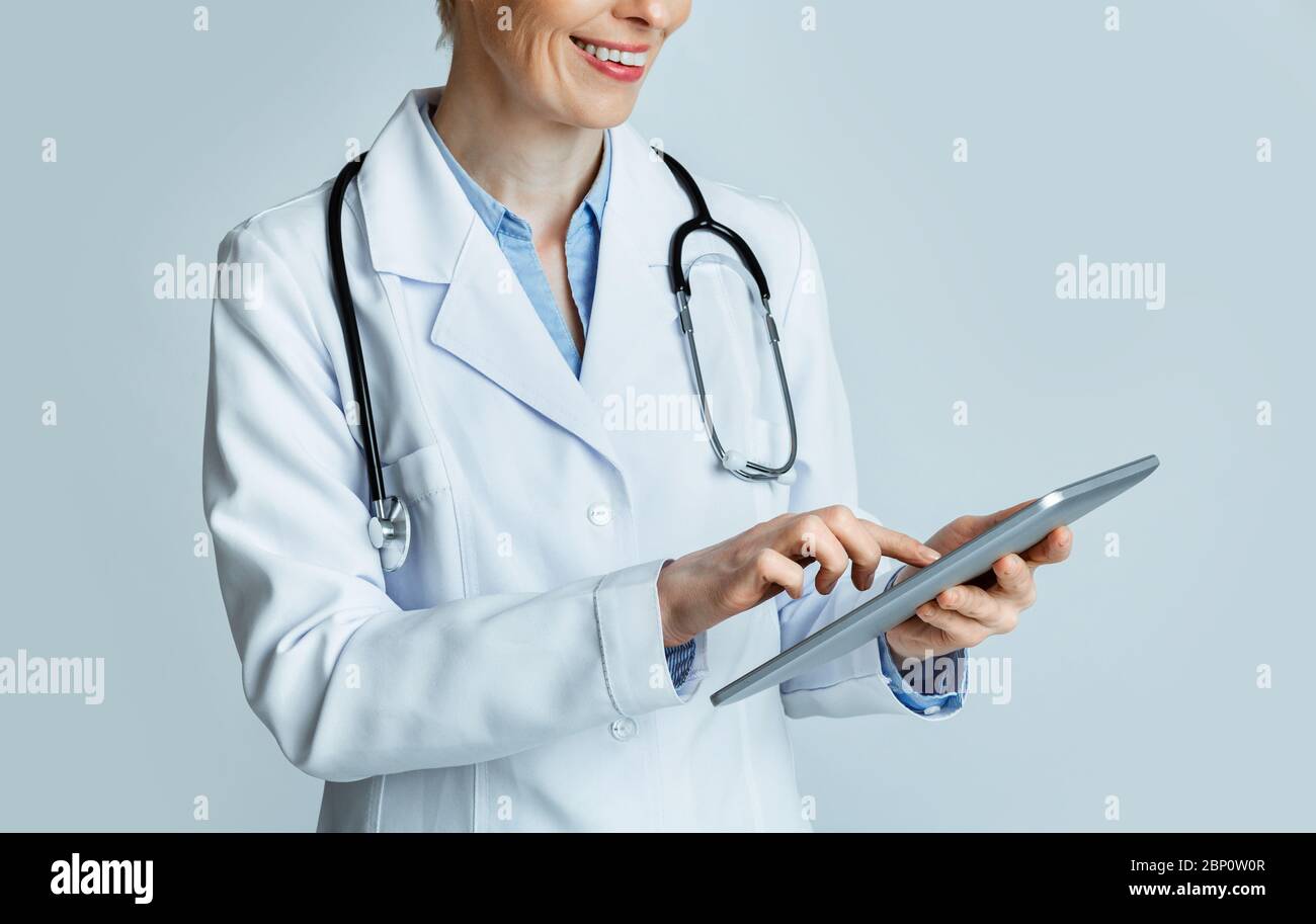 Lächelnde Erwachsene Frau Arzt suchen Krankengeschichte in Tablette Stockfoto