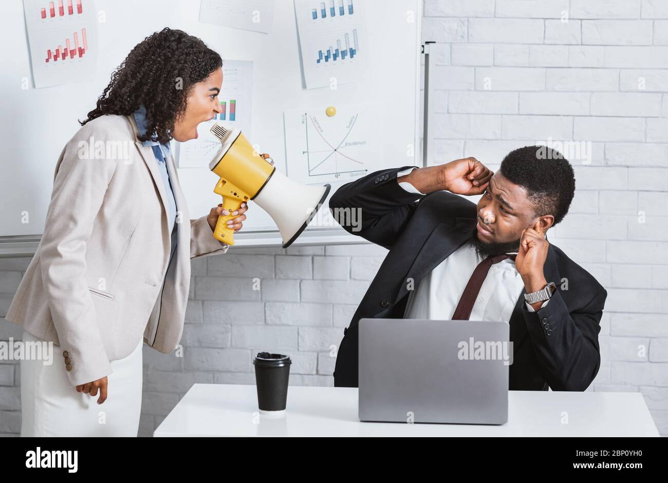 Erzürnte weibliche Chefin mit Lautsprecher schreit auf untergeordnete in der Firma Büro Stockfoto