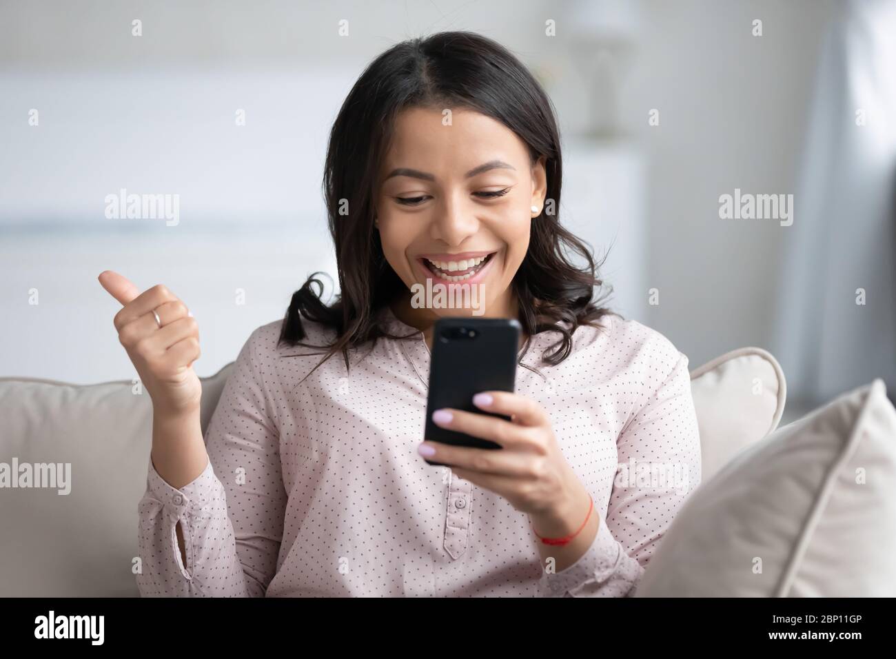 African weiblich hält Smartphone fühlt sich überglücklich zeigen Daumen hoch Stockfoto