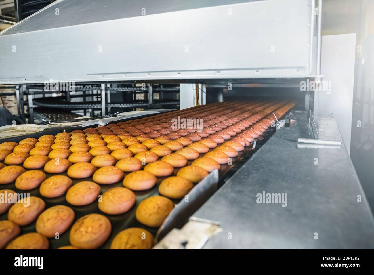 Automatisches Förderband mit Kuchen, Backprozess in der Süßwarenfabrik. Lebensmittelindustrie, getönte Stockfoto
