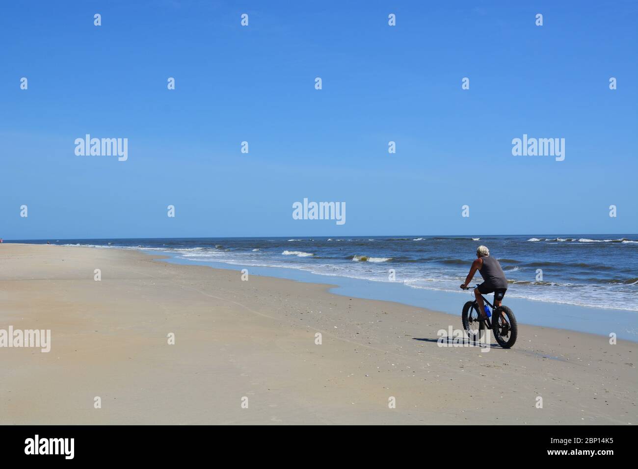 Ein Mann fährt mit dem Fahrrad entlang der Küste in Nags Head an den Outer Banks von North Carolina. Stockfoto