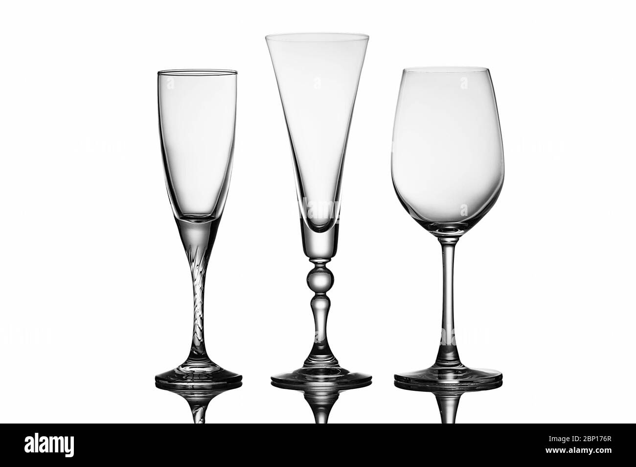 Drei elegante Gläser mit verschiedenen Formen, mit Weinglas und Sektflöten über einem reflektierenden weißen Hintergrund Stockfoto