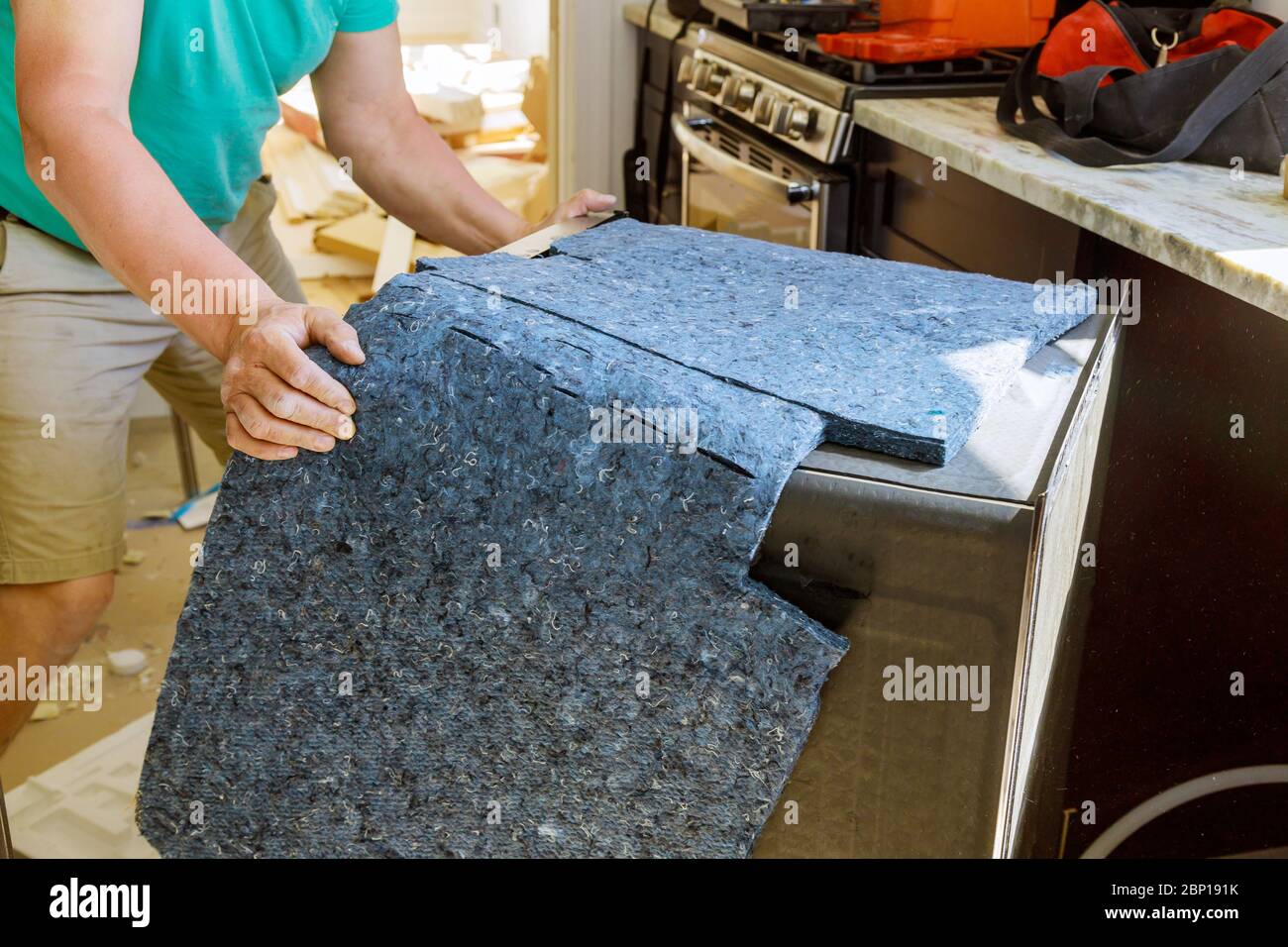 Männlicher Techniker repariert Geschirrspüler in der Küche auf neuem Haus Stockfoto