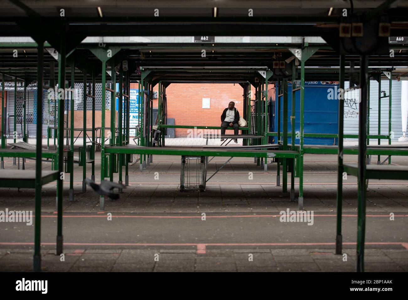 Ein Mann sitzt auf dem verlassenen Bullring Open Market in Birmingham, nachdem Maßnahmen eingeführt wurden, um das Land aus der Blockierung zu bringen. Stockfoto