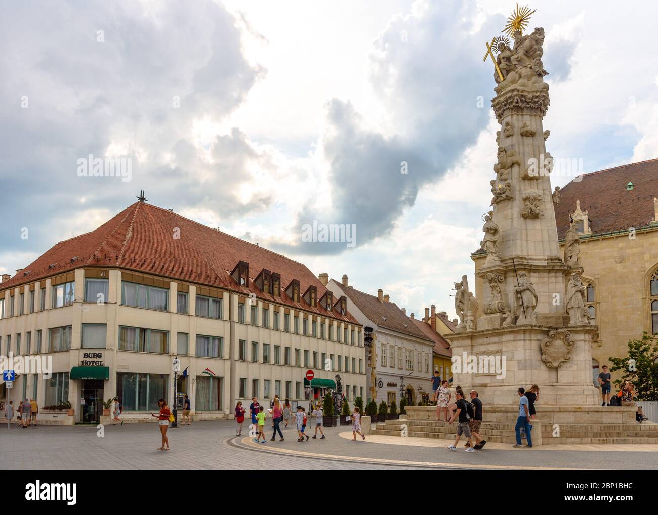Touristen stehen vor der Heiligen Dreifaltigkeit Statue aus dem 18. Jahrhundert auf dem Szentheromsag ter im Budaer Burgviertel mit dem Burg Hotel im Hintergrund Stockfoto