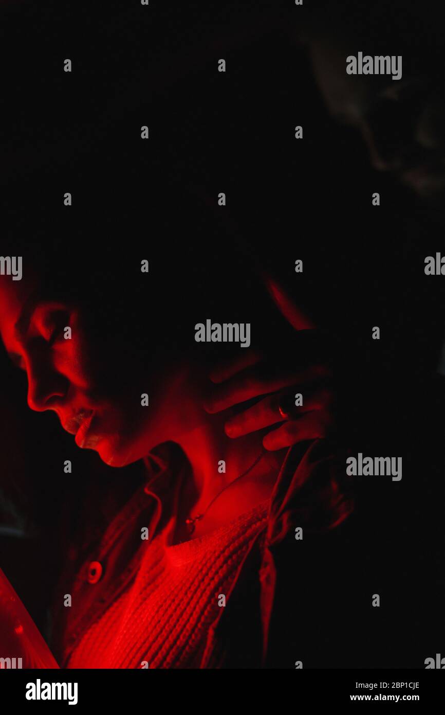 Mann berührt ihren Frauenhals in Neonlicht Stockfoto