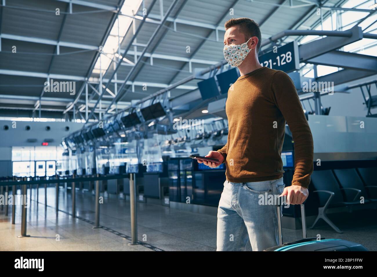 Mann mit Gesichtsmaske und zu Fuß im Flughafenterminal. Themen Reisen während der Pandemie und persönlichen Schutz. Stockfoto