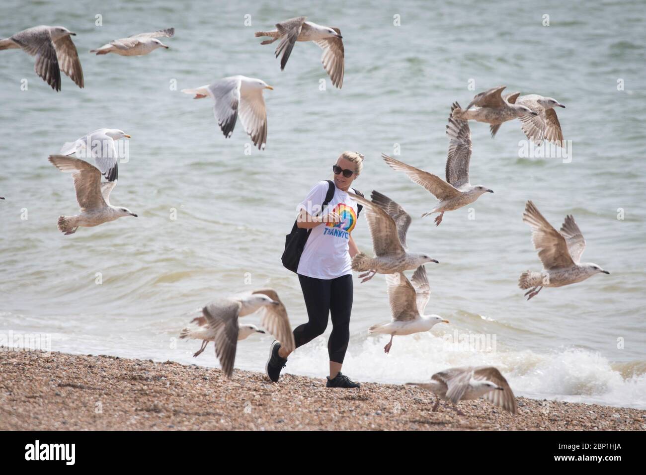 Eine Dame, die ein T-Shirt trägt und dem NHS dankt, geht heute an einem langen Strand von Brighton entlang, während Großbritannien weiterhin in der Lockdown-Richtung bleibt, um die Ausbreitung des Coronavirus einzudämmen. PA-Foto. Bilddatum: Sonntag, 17. Mai 2020. Siehe PA Geschichte GESUNDHEIT Coronavirus. Foto-Kredit sollte lauten: Stefan Rousseau/PA Wire Stockfoto