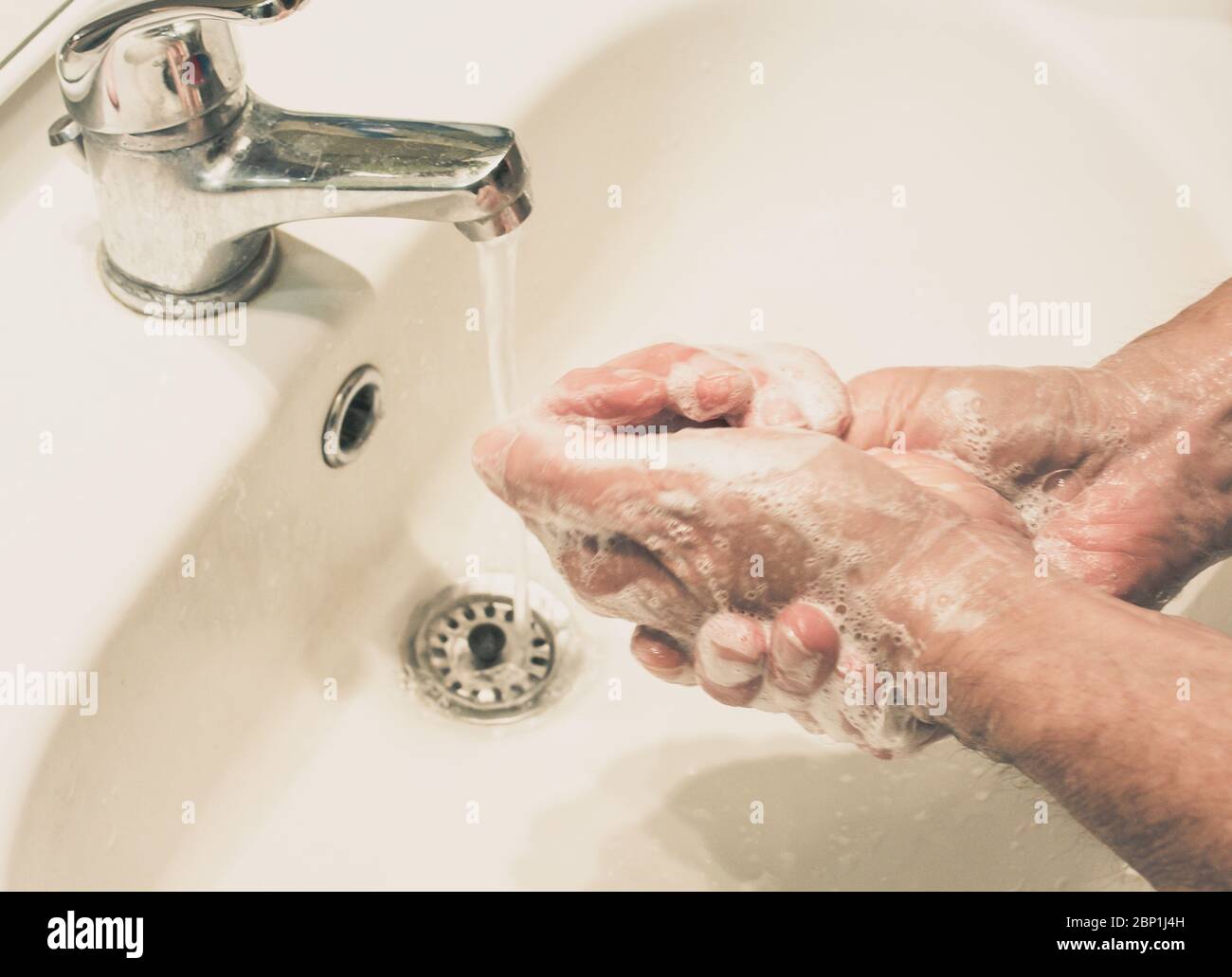 Reifer Mann wäscht sich die Hände mit fließendem Wasser und Seife. Schutz vor Infektionen. Waschen Sie Ihre Hände gegen das Virus Stockfoto