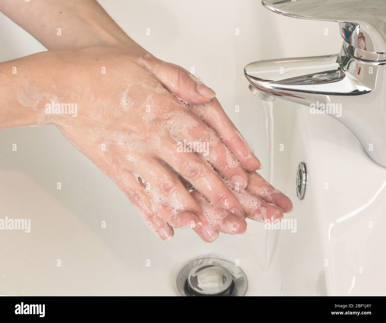 Frau wäscht sich die Hände mit fließendem Wasser und Seife. Schutz vor Infektionen Stockfoto