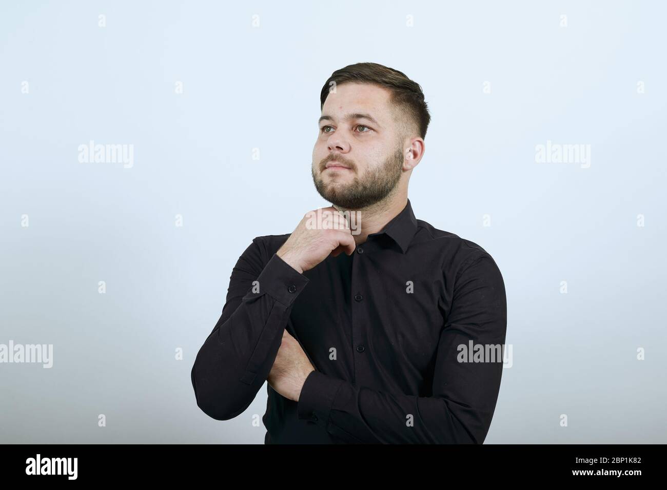 Dreamy Male Hält Hand An Sein Chin Und Denkt. Das Konzept Der Intelligenten Menschen Stockfoto