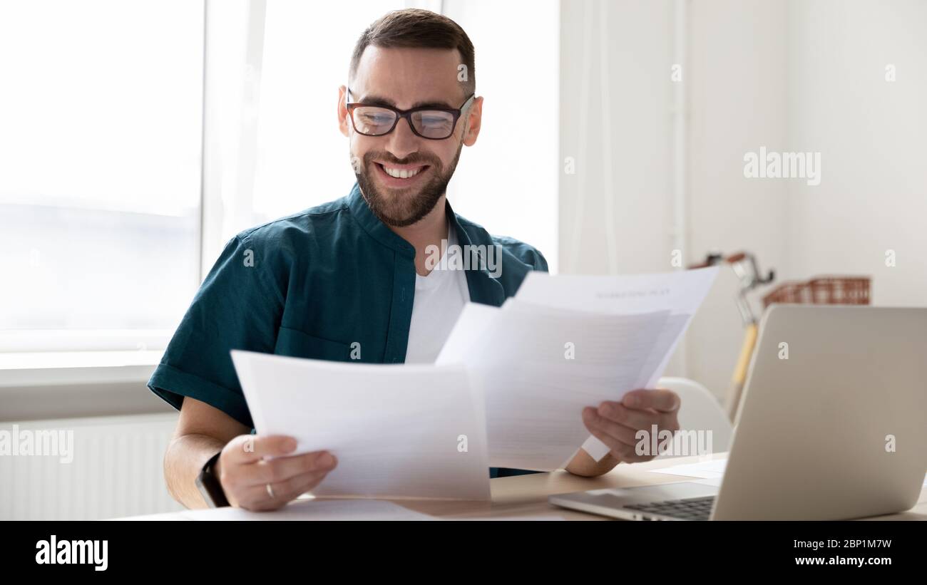 Glücklich gut aussehenden Geschäftsmann hält und liest Dokumente mit guten Nachrichten. Stockfoto