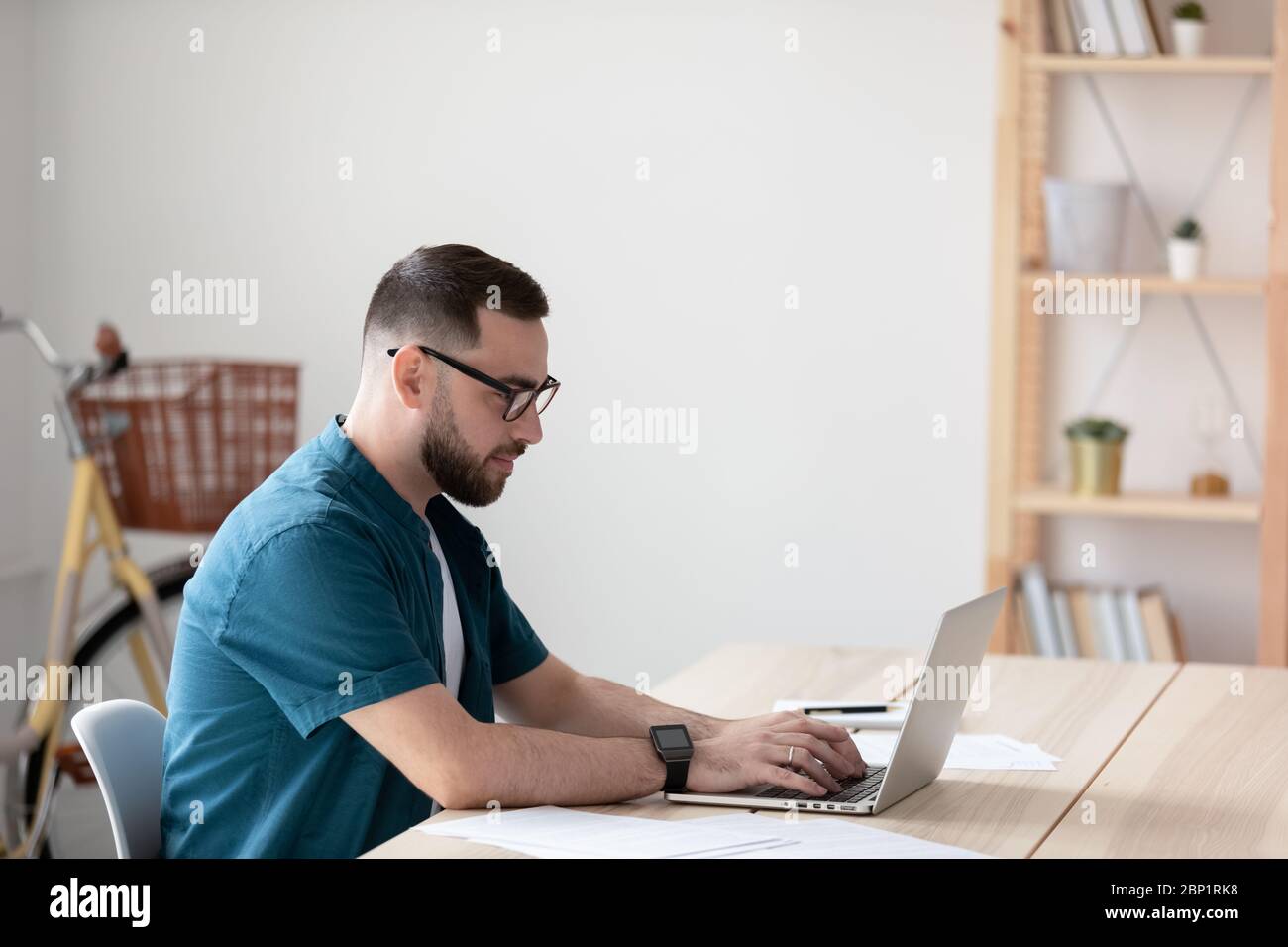 Seitenansicht schöner junger Geschäftsmann Eingabe auf der Tastatur mit Laptop. Stockfoto