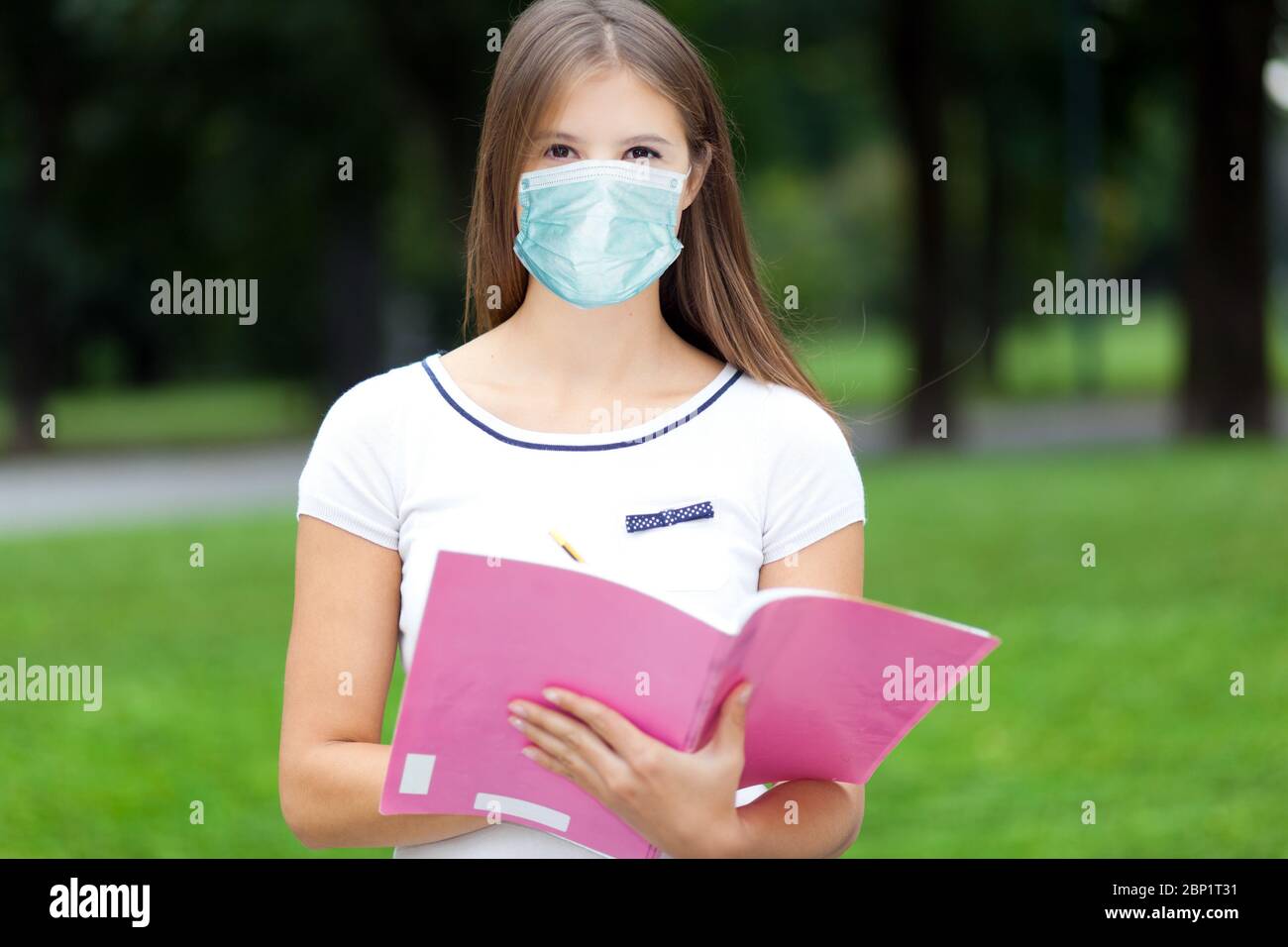 Schöne weibliche College-Studentin im Freien trägt eine Maske, Coronavirus-Konzept Stockfoto