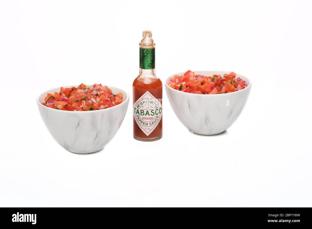 2 identische Schalen mit frisch zubereiteter Salsa mit einer Flasche Tabasco-Sauce Stockfoto