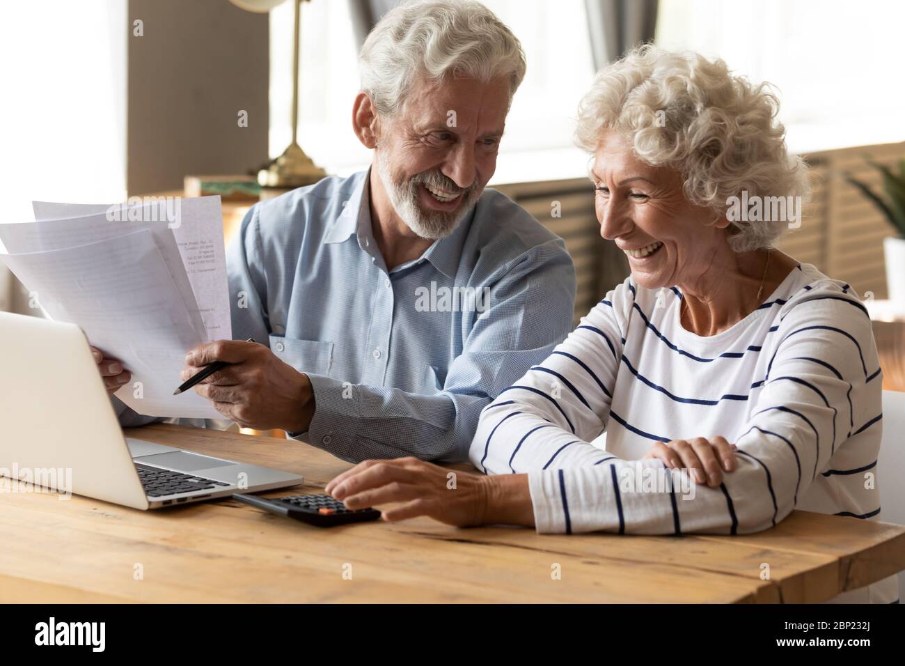 Lächelndes, freundliches reifes älteres Ehepaar, das das monatliche Budget verwaltet. Stockfoto