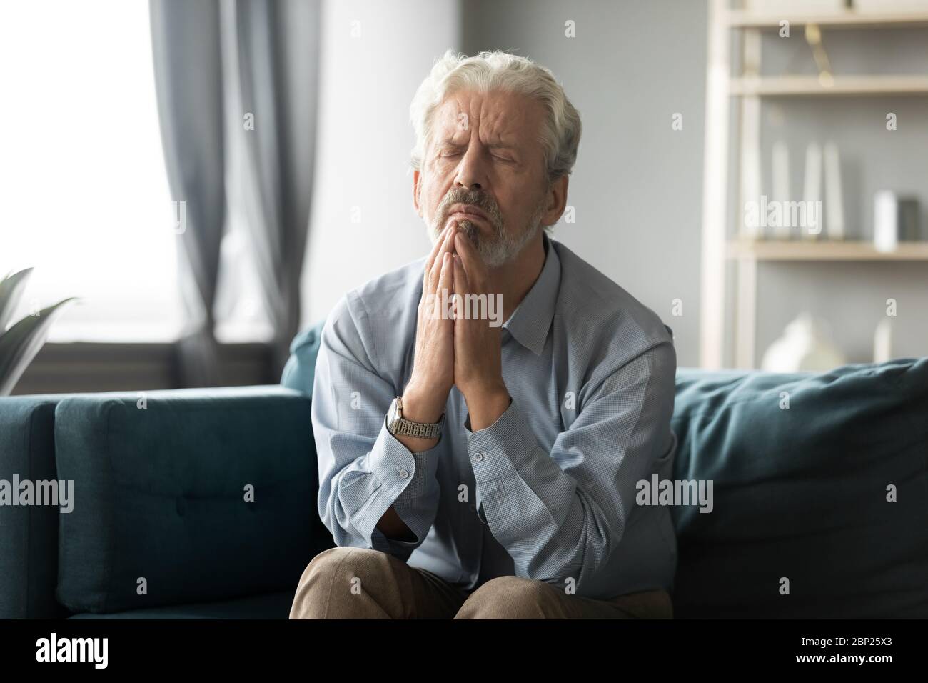 Treuer älterer Mann mittleren Alters betend Gott. Stockfoto