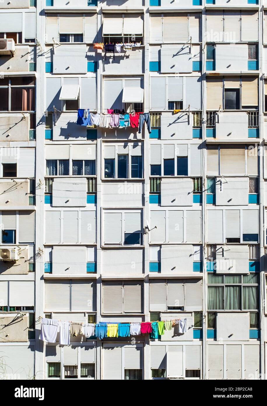 Fenster des mehrstöckigen Wohnhauses mit bunten Kleidung Trocknen auf Trockengestellen. Stockfoto