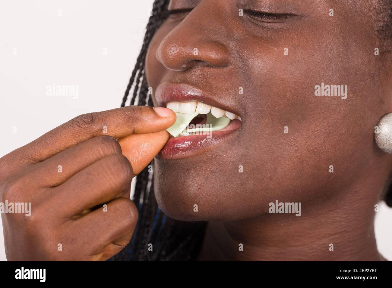 Junges Mädchen, das Kaugummi in den Mund mit geschlossenen Augen legt. Stockfoto