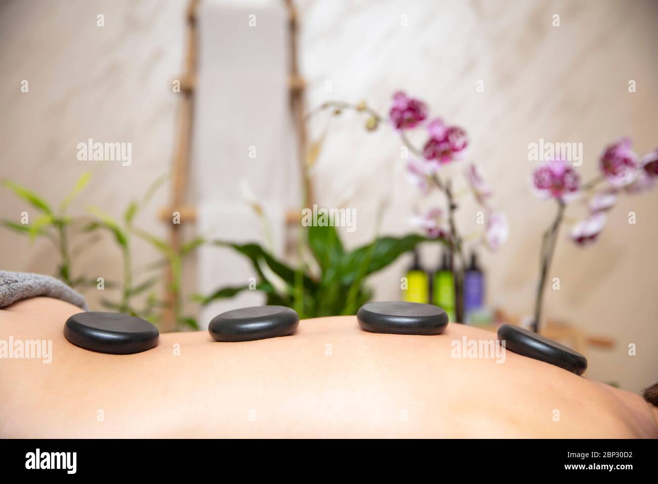 Junge Frau haben ein Wellness-Spa entspannende Stein-Therapie mit heißen vulkanischen Steinen auf dem Rücken Stockfoto