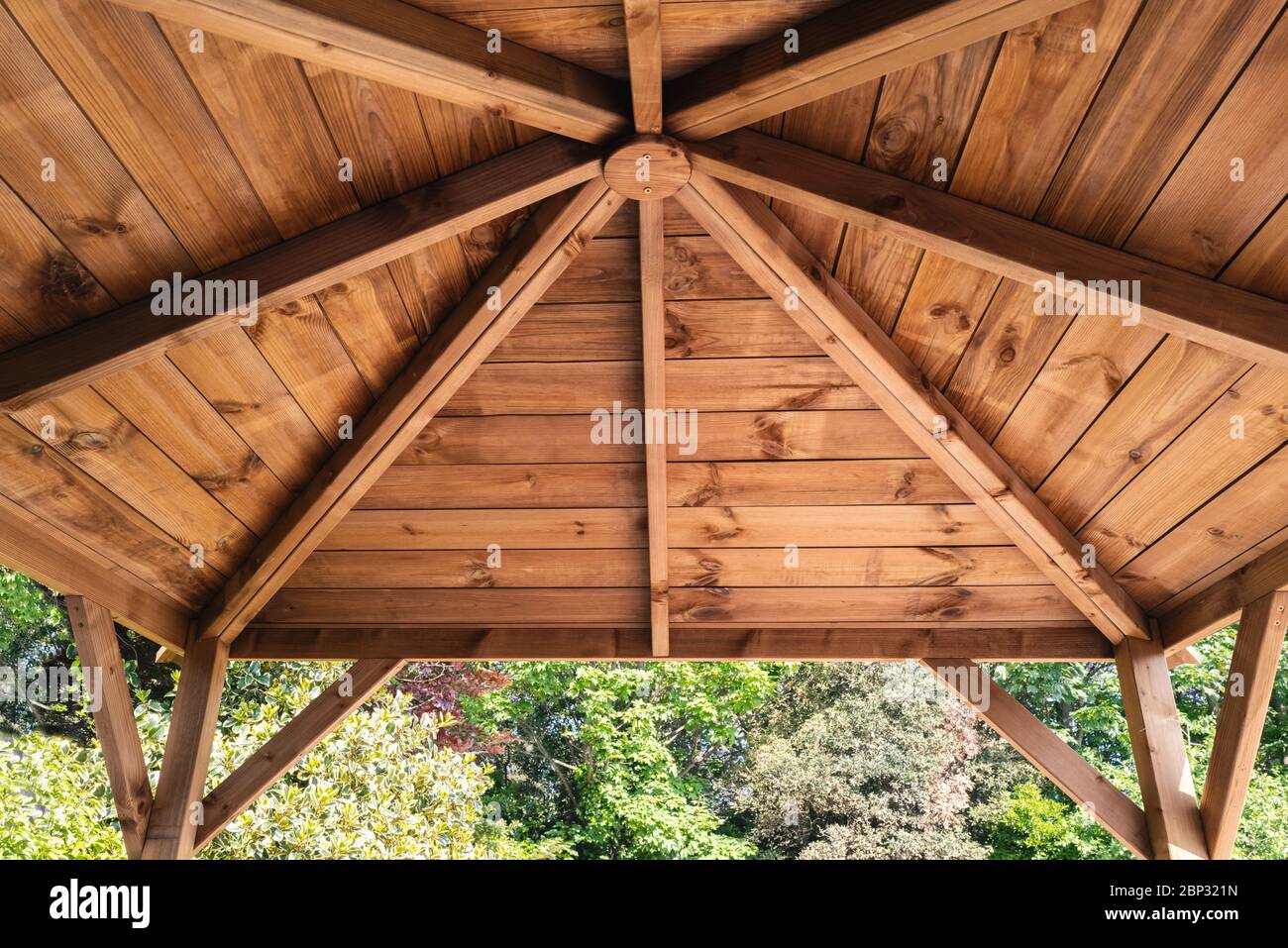 Das Innendach eines hölzernen Gartenpavillons, der von innen nach oben und außen blickt. Stockfoto