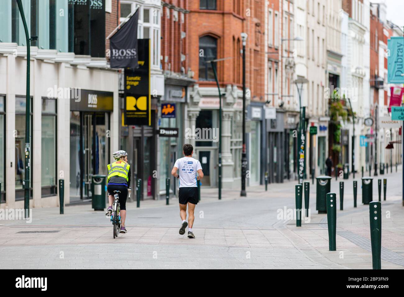 Joggen und Radfahren durch die verlassene Grafton Street im Stadtzentrum von Dublin, während der Fußabsturz aufgrund der Coronavirus-Pandemie abstürzt. Covid-19 in Irland. Stockfoto