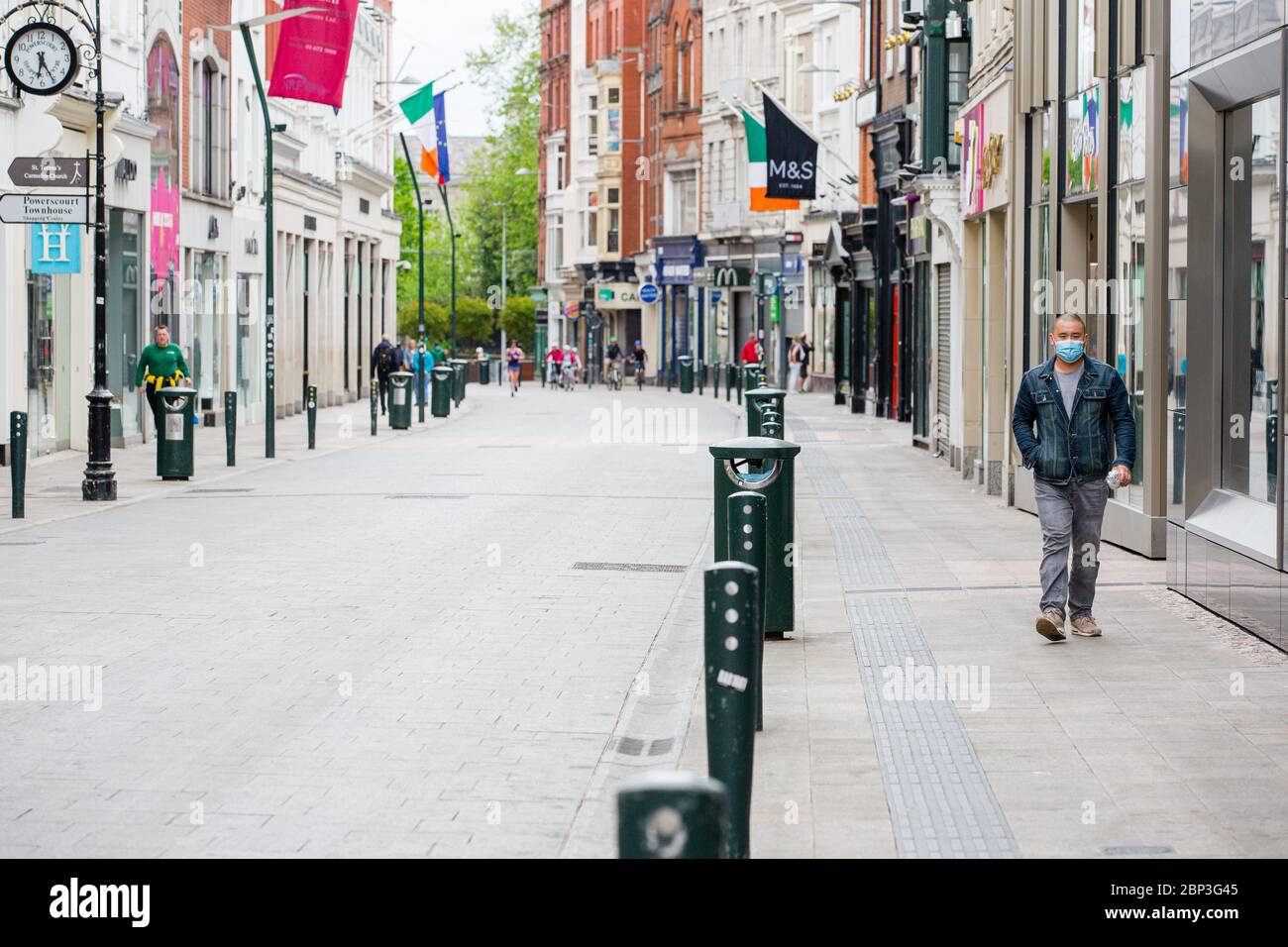 Fußgänger mit Schutzmaske geht durch die verlassene Grafton Street im Stadtzentrum von Dublin, während der Fußabsturz aufgrund der Coronavirus-Pandemie abstürzt. Stockfoto