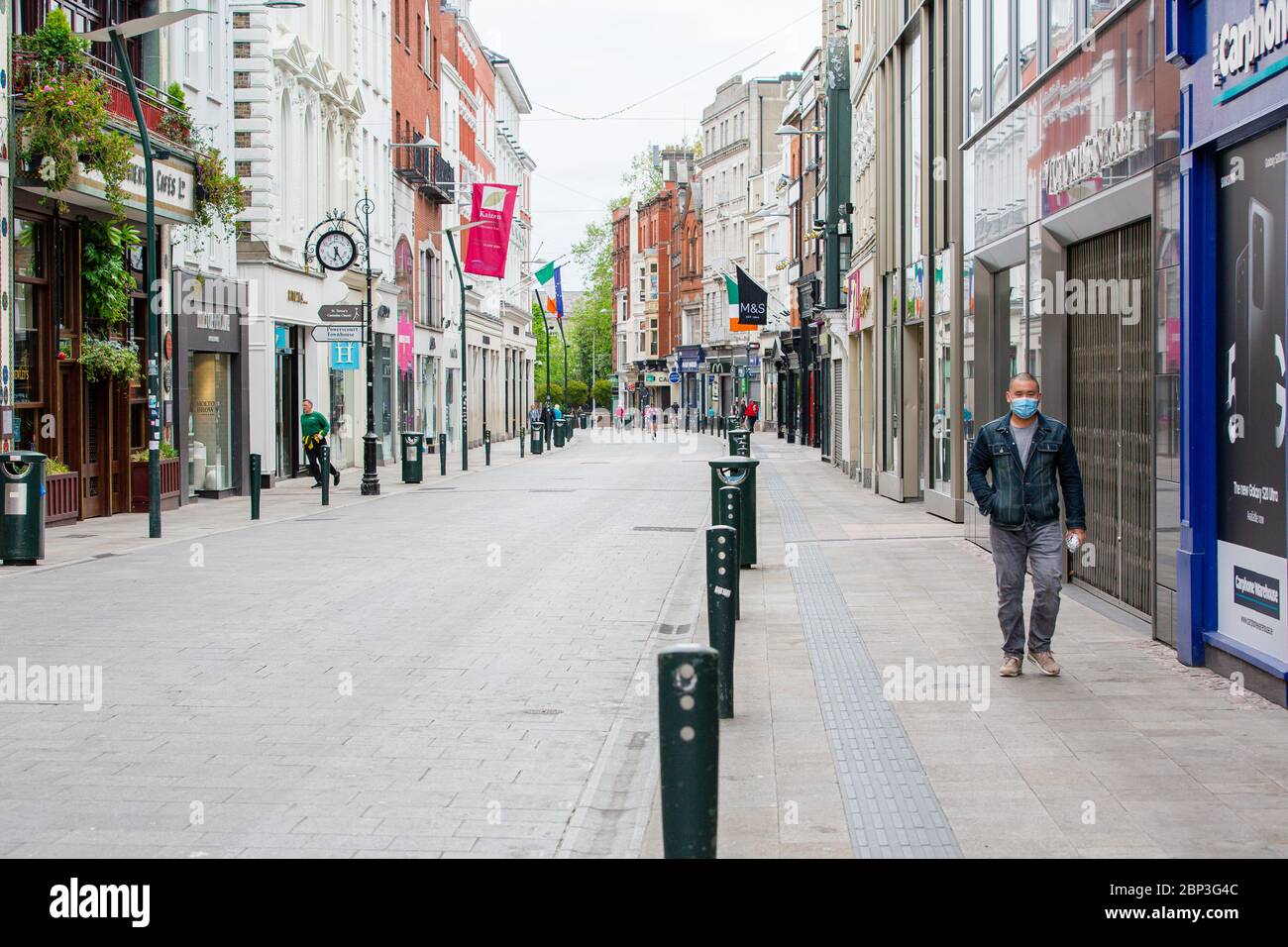 Fußgänger mit Schutzmaske geht durch die verlassene Grafton Street im Stadtzentrum von Dublin, während der Fußabsturz aufgrund der Coronavirus-Pandemie abstürzt. Stockfoto