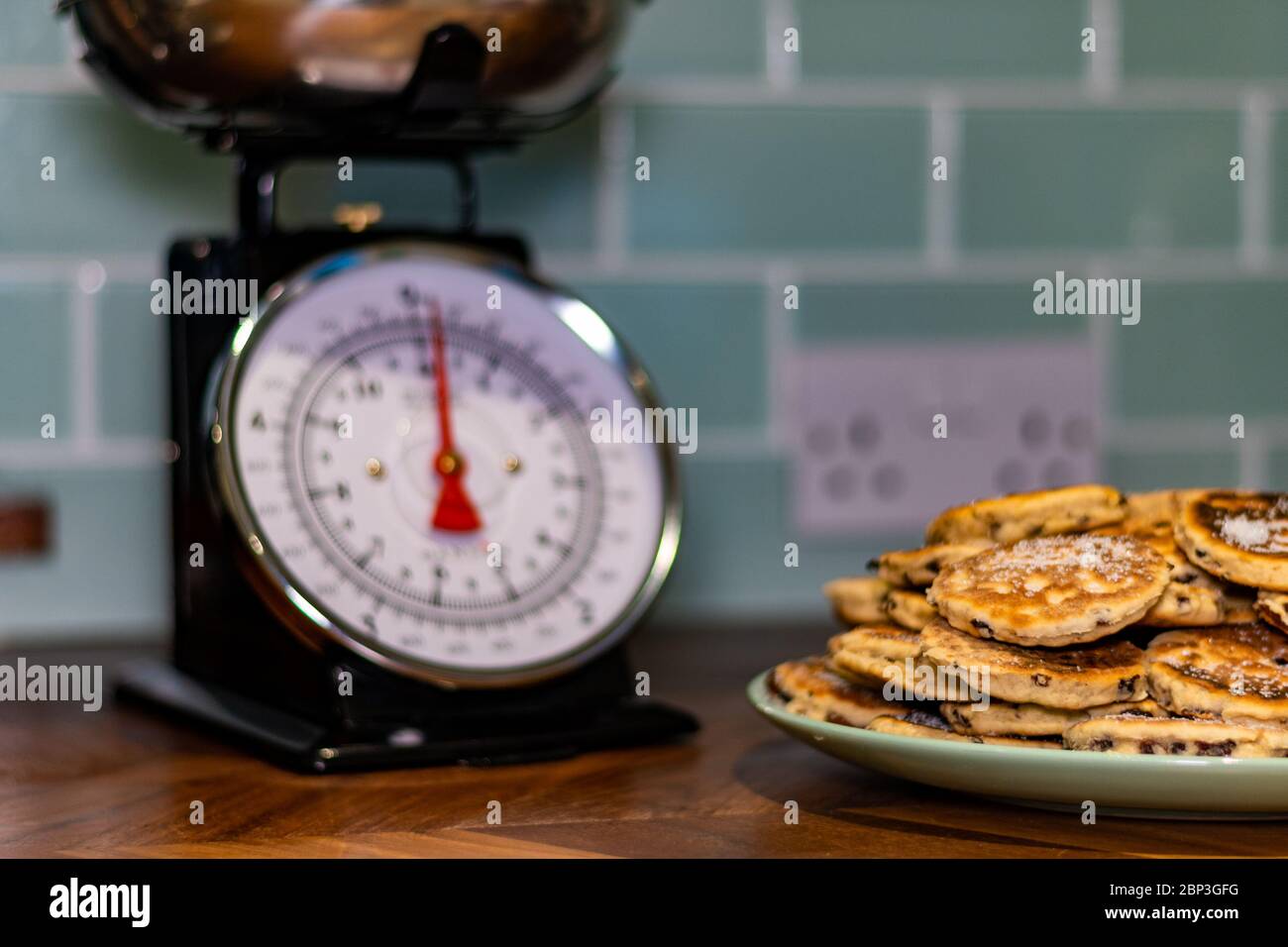 Hausgemachte Welsh Kuchen (Bakestones) isoliert auf grünen Teller mit Waage in Hintergrund verfärbt Stockfoto