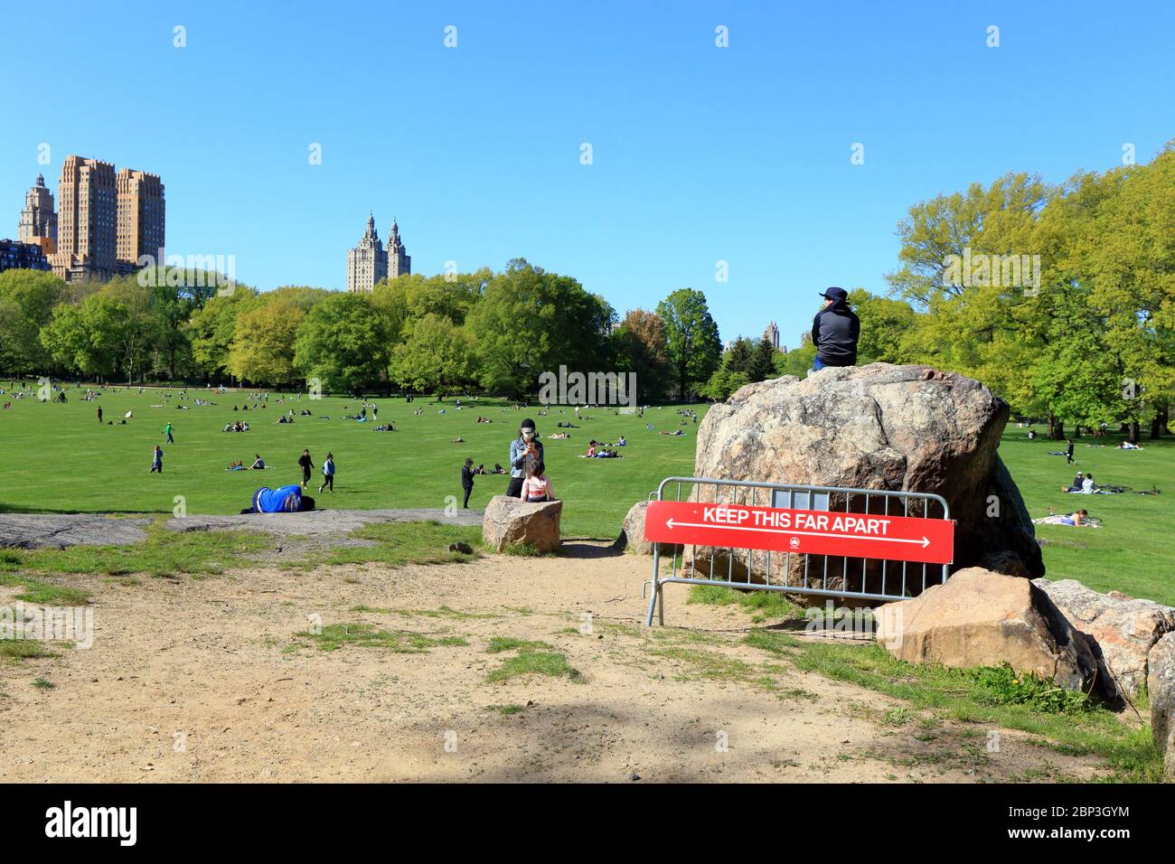 Menschen soziale Distanz in New York Central Park Sheep Meadow mit einem NYC Parks Abteilung sechs Fuß soziale Distanz Zeichen im Vordergrund. Stockfoto