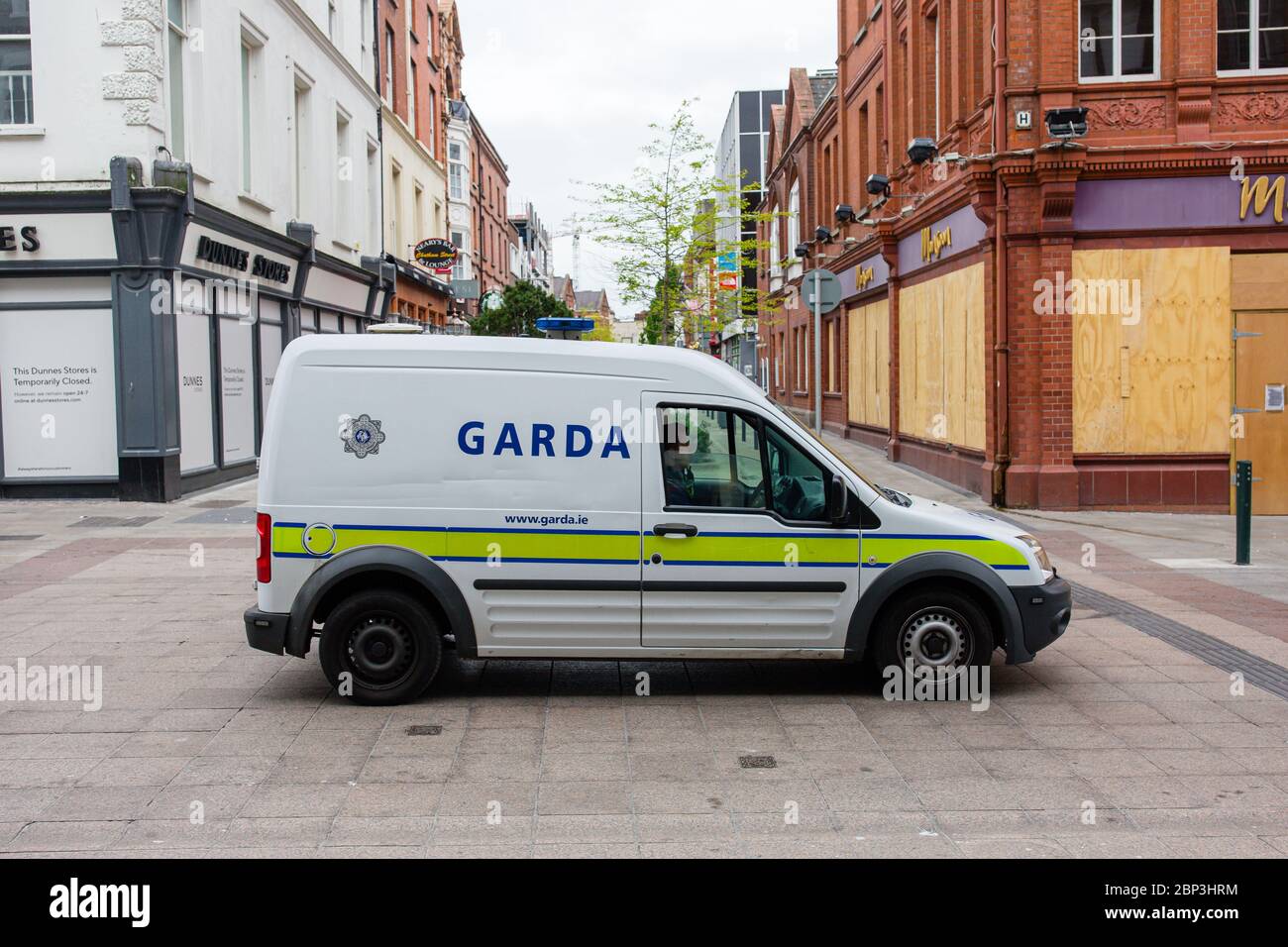 Garda patrouilliert an der Grafton Str. begrenzte Anzahl und Verkehr im Stadtzentrum von Dublin und Geschäfte und Geschäfte sind wegen Covid-19 Pandemiebeschränkungen geschlossen. Stockfoto