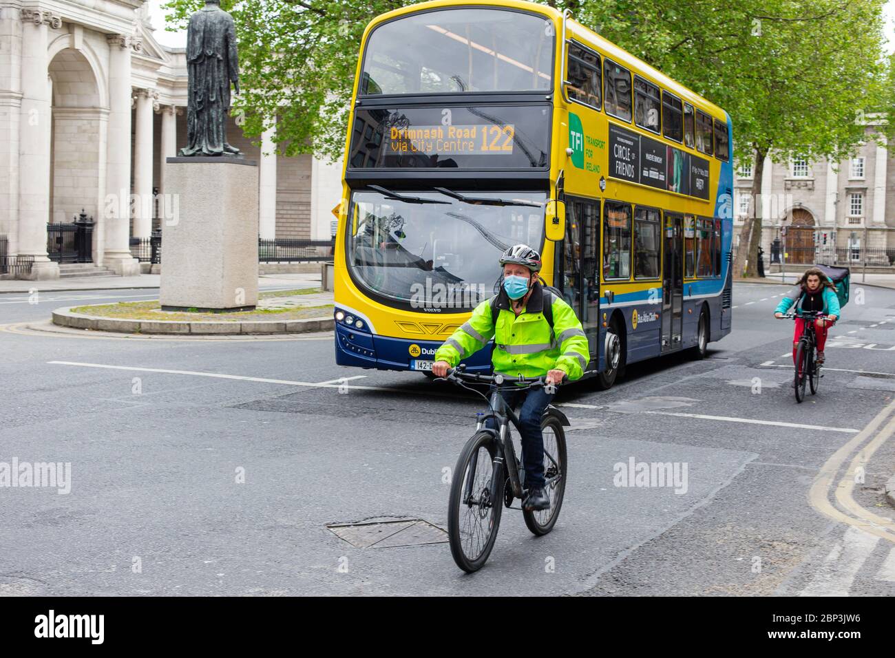 Radfahrer mit Schutzmaske und Dublin Bus durch College Green in Dublin City Centre. Covid-19 Pandemiebeschränkungen. Stockfoto