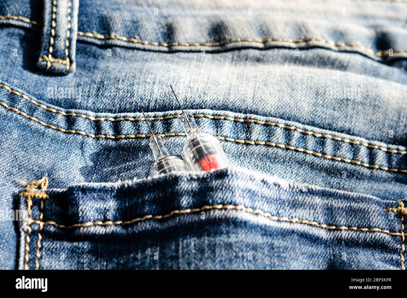 Zwei Spritzen in der Gesäßtasche seiner Hose. Konzept über die sucht nach Injektionen von Drogen . Prävention und Bekämpfung von Drogen bei jungen Menschen Stockfoto