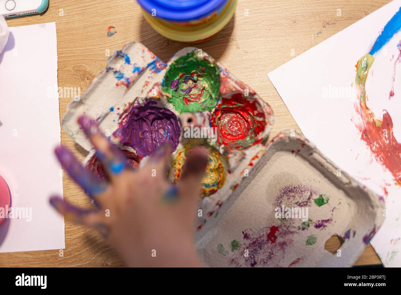 Farbpalette, die Farben auf einem Eizelletui auf einer häuslichen Szene mit Kindern spielt mischen Stockfoto