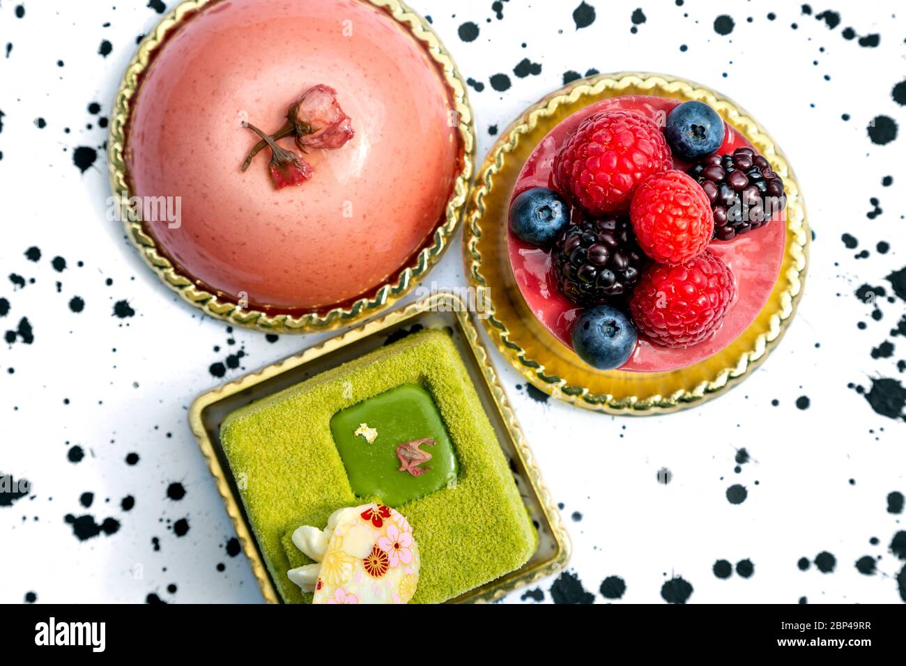 Bunte Kuchen, Mousse, Matcha-Kuchen, garniert mit Beeren Stockfoto