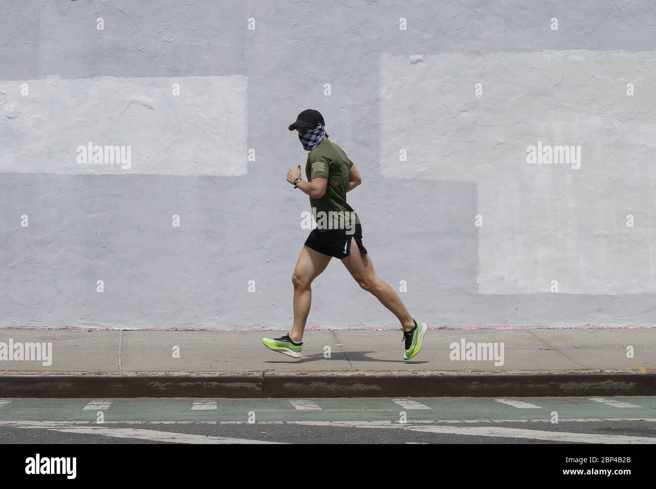 Brooklyn, Usa. Mai 2020. Ein Mann joggt auf einem Seitenweg mit einer schützenden Gesichtsmaske, um die Ausbreitung des Coronavirus in der Nähe des Domino Park in New York City am Sonntag, den 17. Mai 2020 zu verhindern. Weltweit sterben fast 150,000 Menschen pro Tag an COVID-19. Foto von John Angelillo/UPI Quelle: UPI/Alamy Live News Stockfoto
