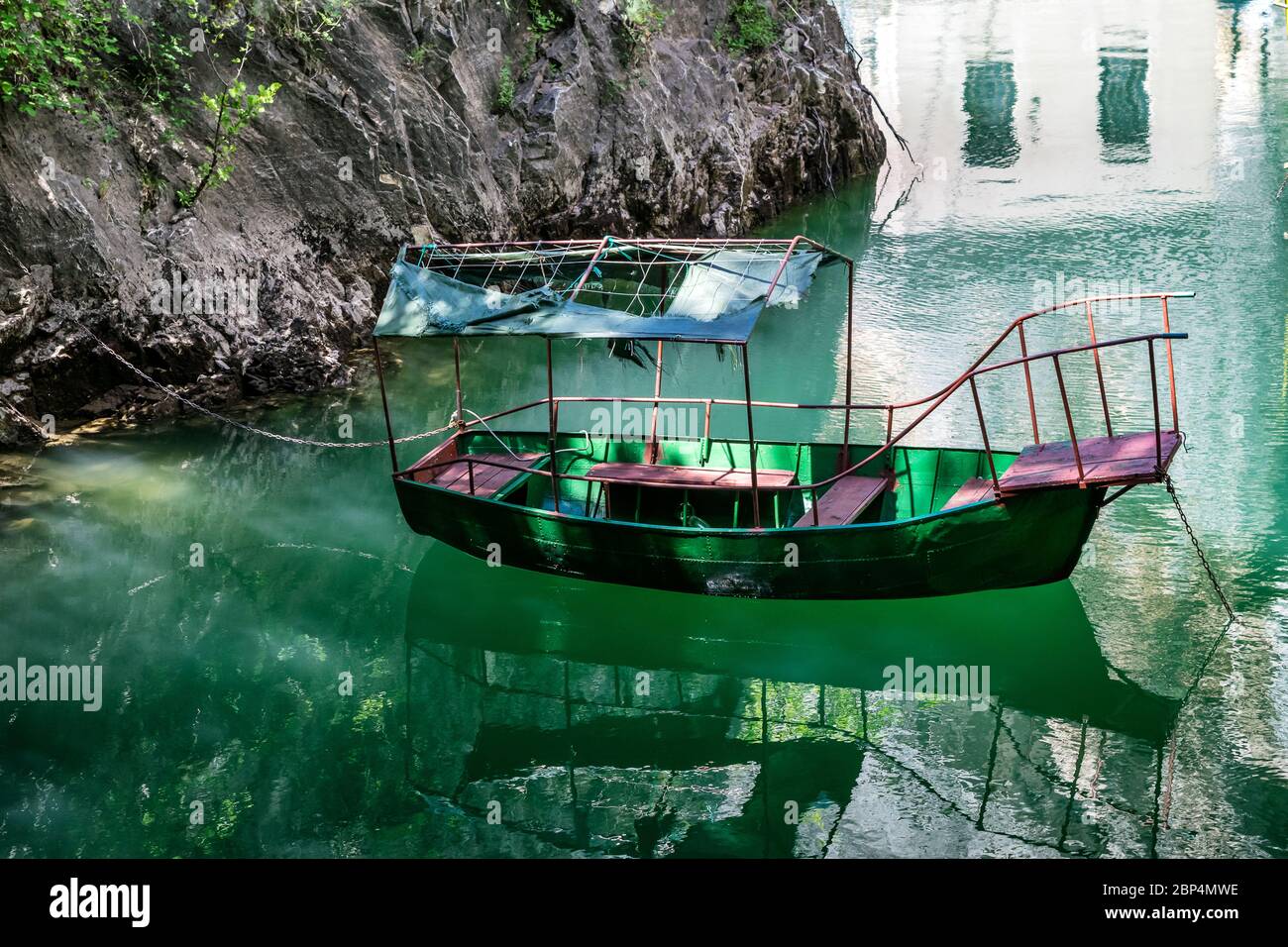 Altes schroffes grünes Boot dockte in der kleinen Bucht am Matka Canyon, Skopje, Mazedonien Stockfoto
