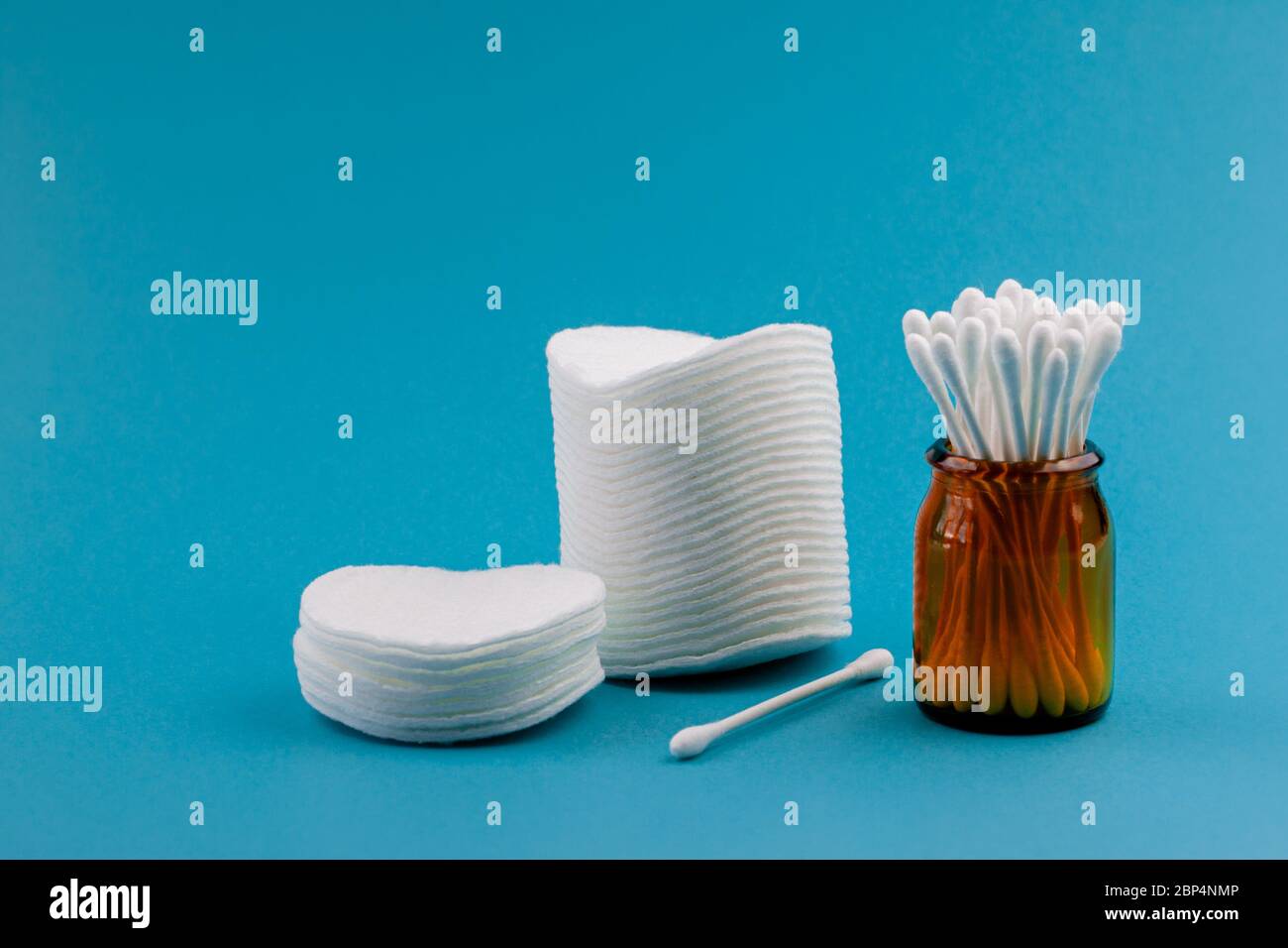 Q-Tips, Wattestäbchen, Wattestäbchen, isoliert auf hellblauem Hintergrund. Gelbe Flasche Stockfoto