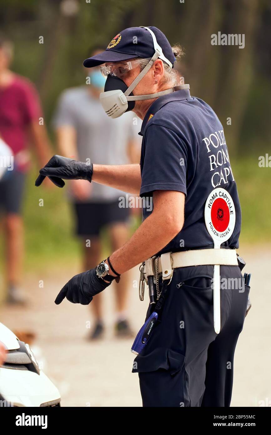 Italienischer Polizist beobachtet die Zusammenkunft der Menschen im Stadtpark Villa Ada in Rom am vergangenen Sonntag, da die Maßnahmen zur sozialen Distanzierung für Phase 2 teilweise aufgehoben werden Stockfoto