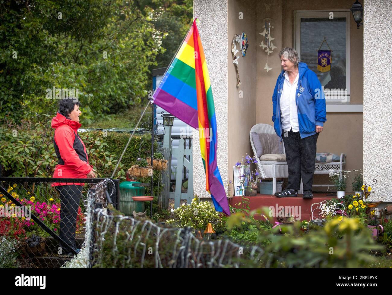 Becs Barker (links) plaudert mit ihrem Nachbarn Jan Brown vor ihrer Haustür in Minard, Argyll und Bute. Eine Handvoll Einwohner des Dorfes stellten eine Gemeinschaftsgruppe auf, um den Schwachen beim Einkaufen zu helfen, wobei die Mehrheit der Dorfbewohner jetzt dabei war, zu helfen und dabei einen neuen Gemeinschaftsgeist durch ihre Bemühungen zur Bekämpfung der Einsamkeit entdeckt zu haben. Stockfoto