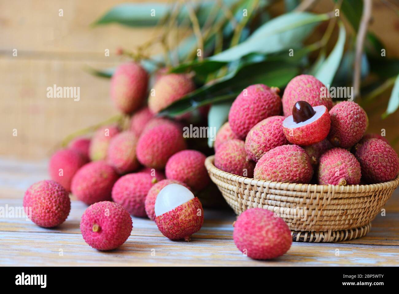 Litschi Scheibe geschält auf Holz / frische Litschi mit grünen Blättern Ernte in Korb von Baum tropische Frucht Sommer in Thailand Stockfoto