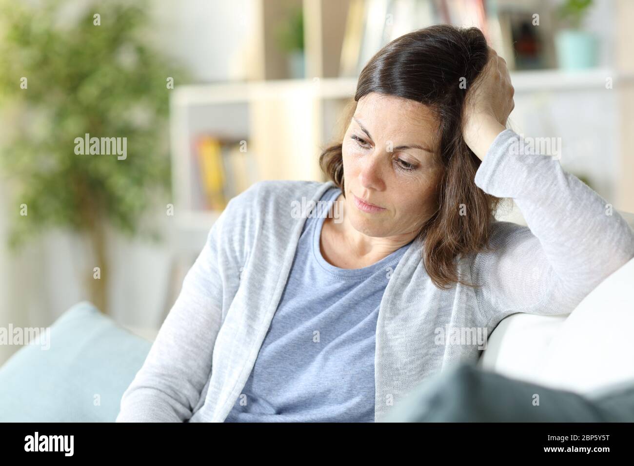 Traurig nachdenkliche Frau mittleren Alters denken, unten sitzend auf einer Couch zu Hause zu sehen Stockfoto