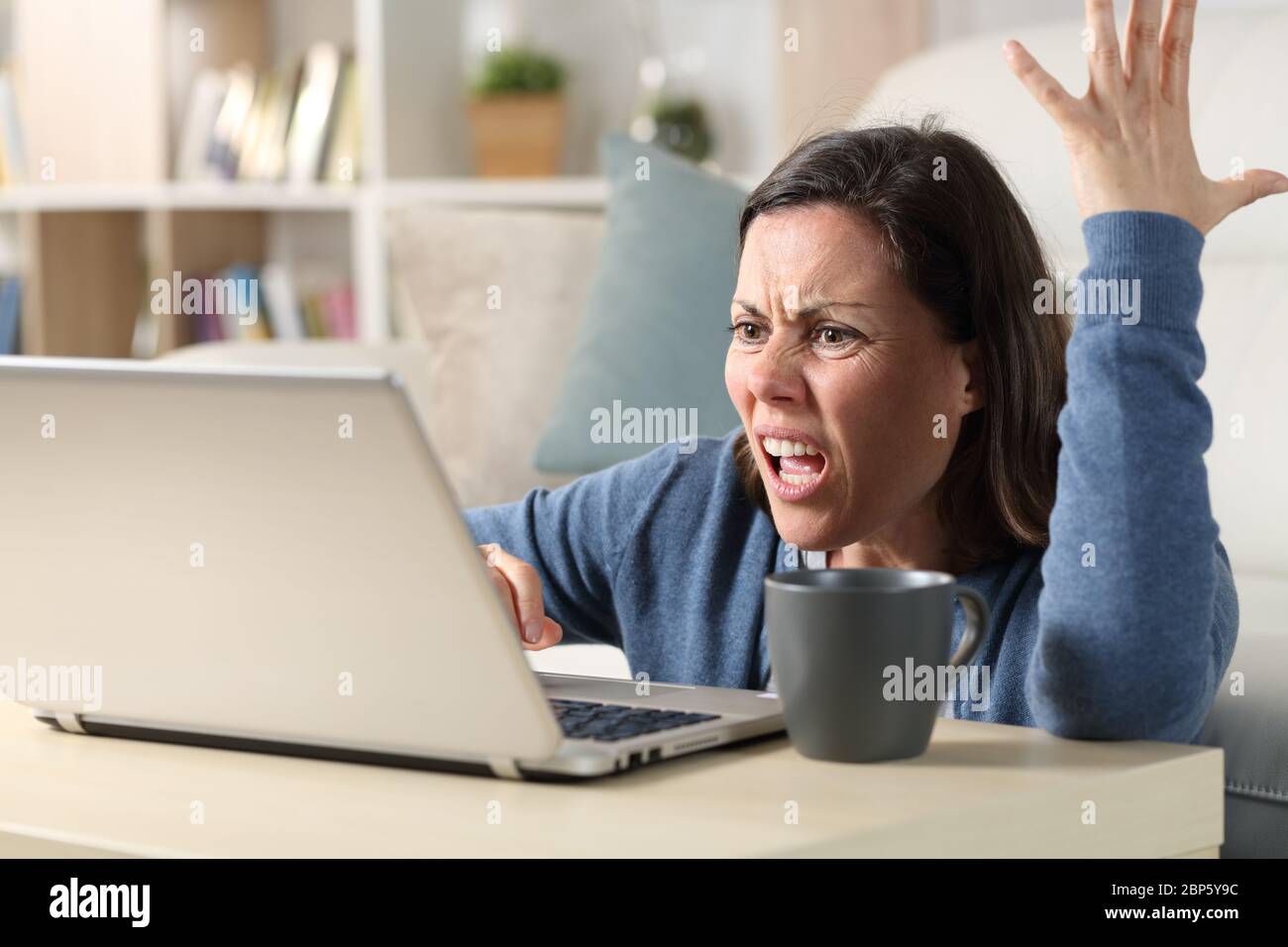 Wütend Erwachsene Frau Online-Video auf Laptop sitzen auf dem Boden zu Hause Stockfoto