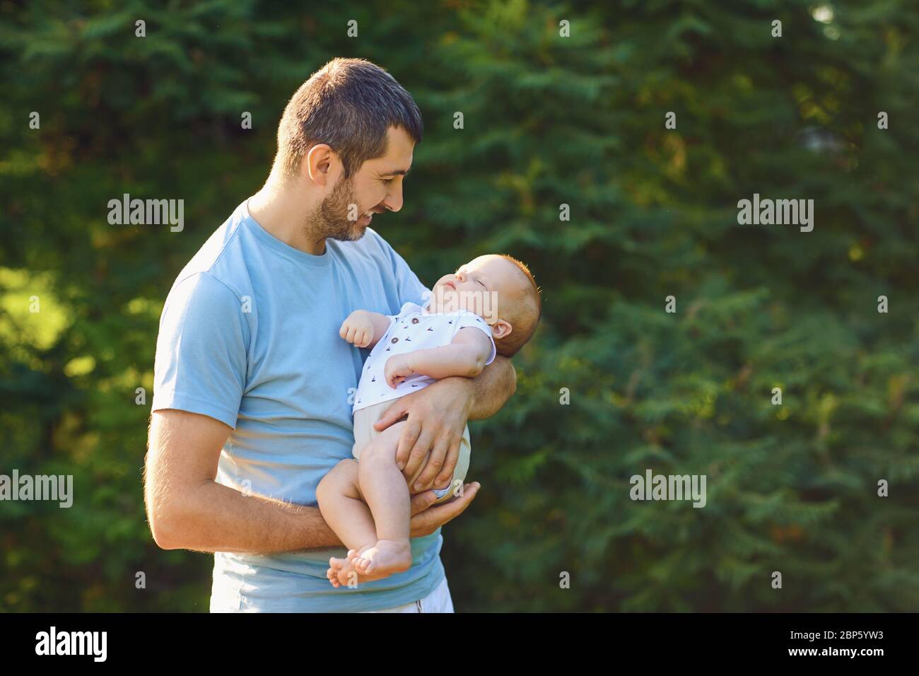 Vatertag. Der fürsorgliche Vater hält das Baby im Park in den Armen Stockfoto