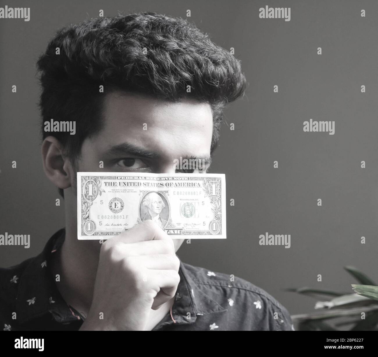 Junger Mann hält Dollarschein vor seinem Gesicht . ein Dollar. Stockfoto
