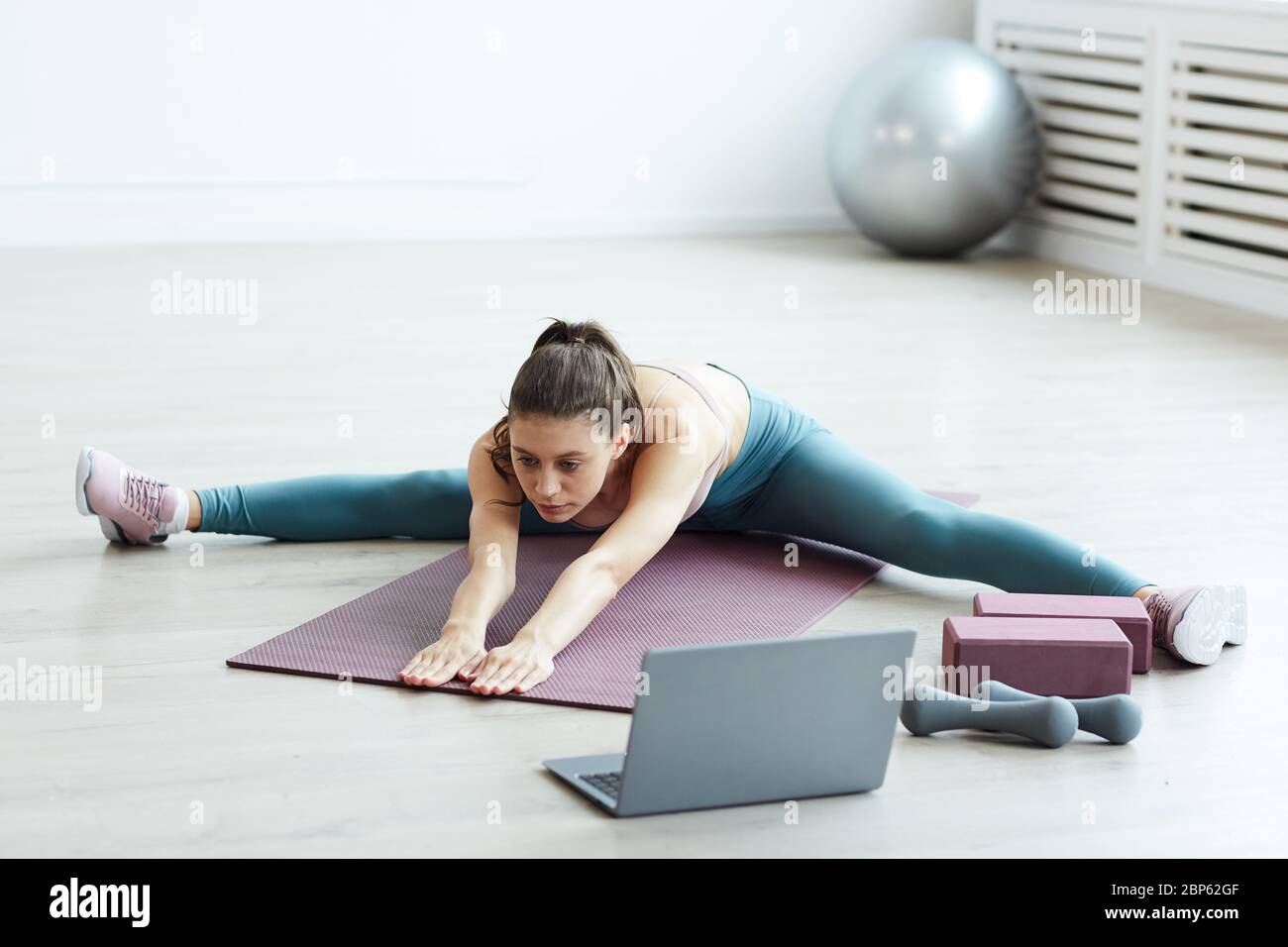 Minimal in voller Länge Porträt von fit junge Frau Splits und Stretching beim Workout zu Hause in weißen Raum, kopieren Raum Stockfoto